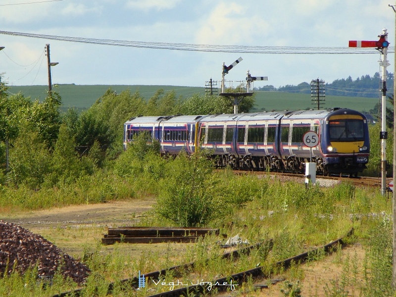 A First ScotRail nevű vasúttársaság 170 452 pályaszámú motorvonata a „Turbostar”, egy Bombardier gyártotta diesel motorvonat, ami 160 km/ó sebességre is képes. A háromrészes motorvonat gyakran, mint itt a képen is egy 158-as sorozatú „Express Spinters” motorvonattal csatolva közlekedik. A képen további érdekesség a még alkalmazott karos jelző és a közúti közlekedésből jól ismert maximális megengedett sebességet jelölő tábla lehet. kép Invernessből Aberdeenbe közlekedő vonat érkezik Inverurie állomásra fotó