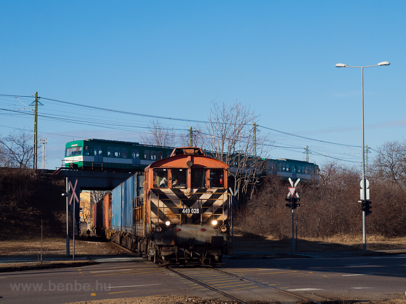 A MÁV-REC 449 028 konténervonatot húz ki Szabadkikötőből Soroksári útra, a háttérben a Csepeli HÉV MX/A vonata
 fotó