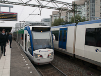 Villamos indul az alacsonyperon mellől Den Haag - Laan van NOI állomáson, a háttérben egy metró (Randstad Rail), elöl pedig már a metró magasperonja