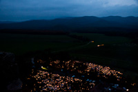 On All Saints' Day, the cemetery of Ngrd is covered by candles. In the background a Bzmot multiple unit is descending between Disjenő and Ngrd stations in front of the background of the High Brzsny Mountains.