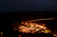 On All Saints' Day, the cemetery of Ngrd is covered by candles. In the background a Bzmot multiple unit is descending between Disjenő and Ngrd stations in front of the background of the High Brzsny Mountains.