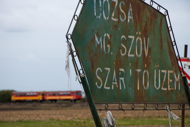 A MV-START 117 201 Borsihalom s Kismindszenti t kztt, a Dzsa Mezőgazdasgi Termelő Szvetkezet (Dzsa MGTSZ) szrtzemt hirdető tbla mellett fot