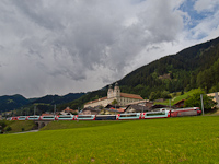 The RhB Ge 4/4<sup>III</sup> 645 is pulling the Glacier-Express panoramicout of Disentis/Mustér station with the abbey in the background
